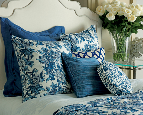 six custom blue Calico pillows on a bed in a variety of patterns and styles